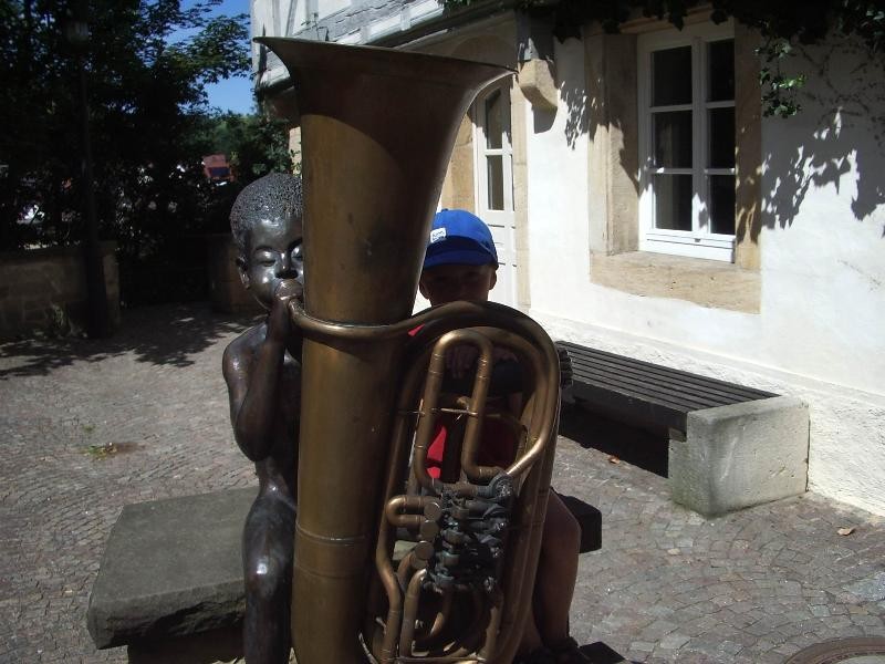 Steinfigur eines kleinen Jungen mit seiner Tuba